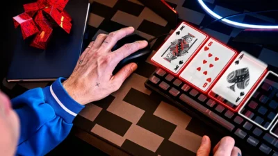Un primo piano della mano di un giocatore di poker su un mouse con carte da gioco digitali sulla tastiera, a rappresentare il processo decisionale del poker online.