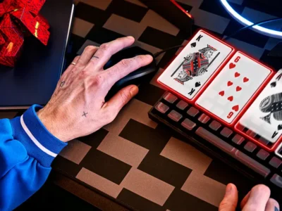 Un primo piano della mano di un giocatore di poker su un mouse con carte da gioco digitali sulla tastiera, a rappresentare il processo decisionale del poker online.