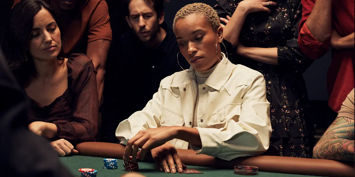 Giocatrice di poker che pensa a come rispondere a un avversario particolarmente aggressivo, mettendo in evidenza la difficoltà nel passare dopo aver investito delle chips nel piatto.