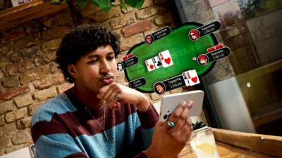 Giocatore di poker che gioca sul suo smartphone. In sovraimpressione si vede un tavolo di poker virtuale dove viene mostrata una coppia di donne.